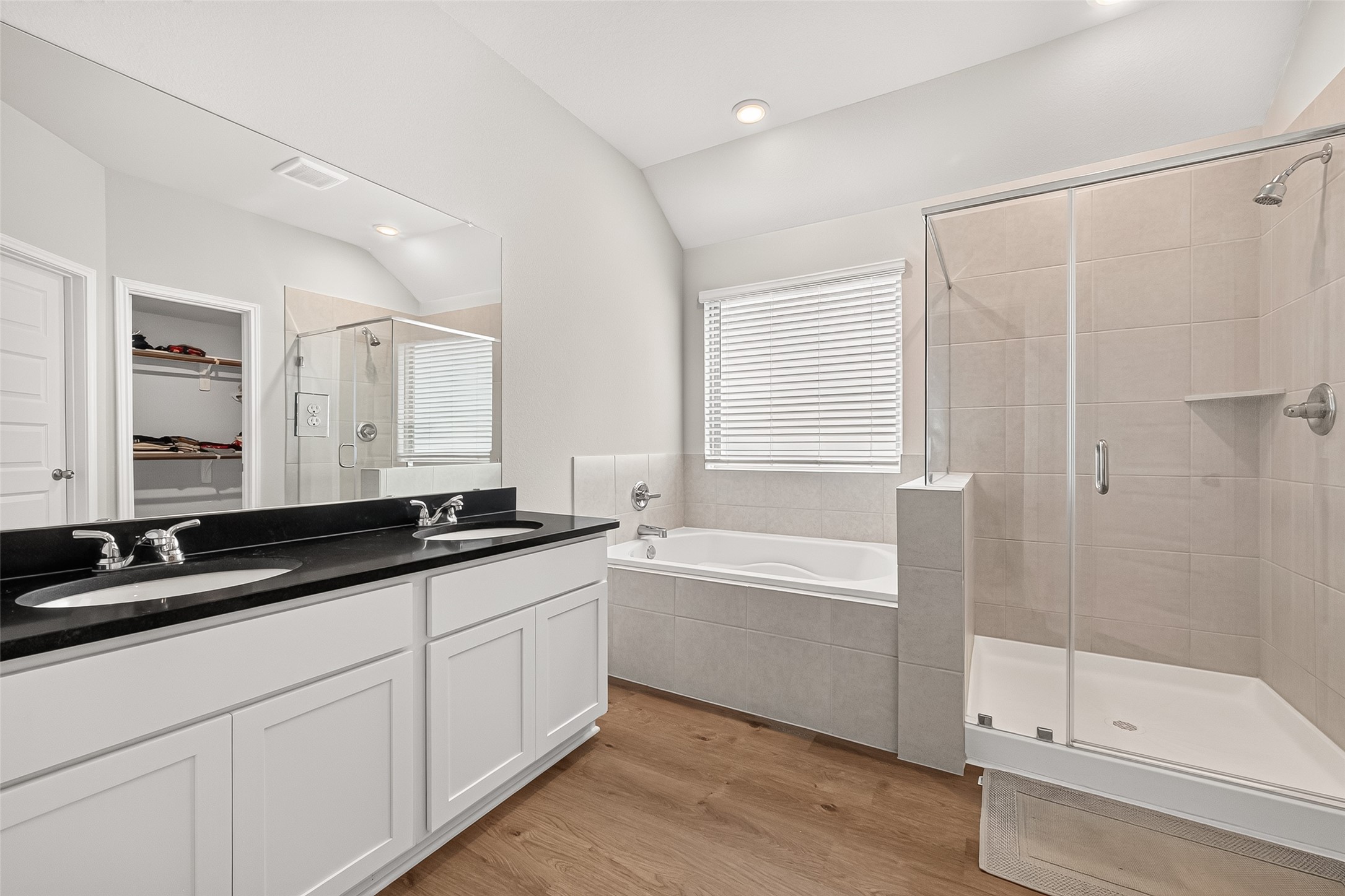 4004 Baja Lane Houston, TX 77045 - Photo 20 of 34 An elegant and sunlit sanctuary. This contemporary primary bath features a crisp double vanity, a modern glass-enclosed shower, and a separate relaxing bathtub. A generous window floods the room with bright, natural light, creating a clean and refreshing atmosphere that is perfect for starting your day.