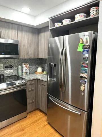 a kitchen with stainless steel appliances granite countertop a refrigerator a sink and a stove