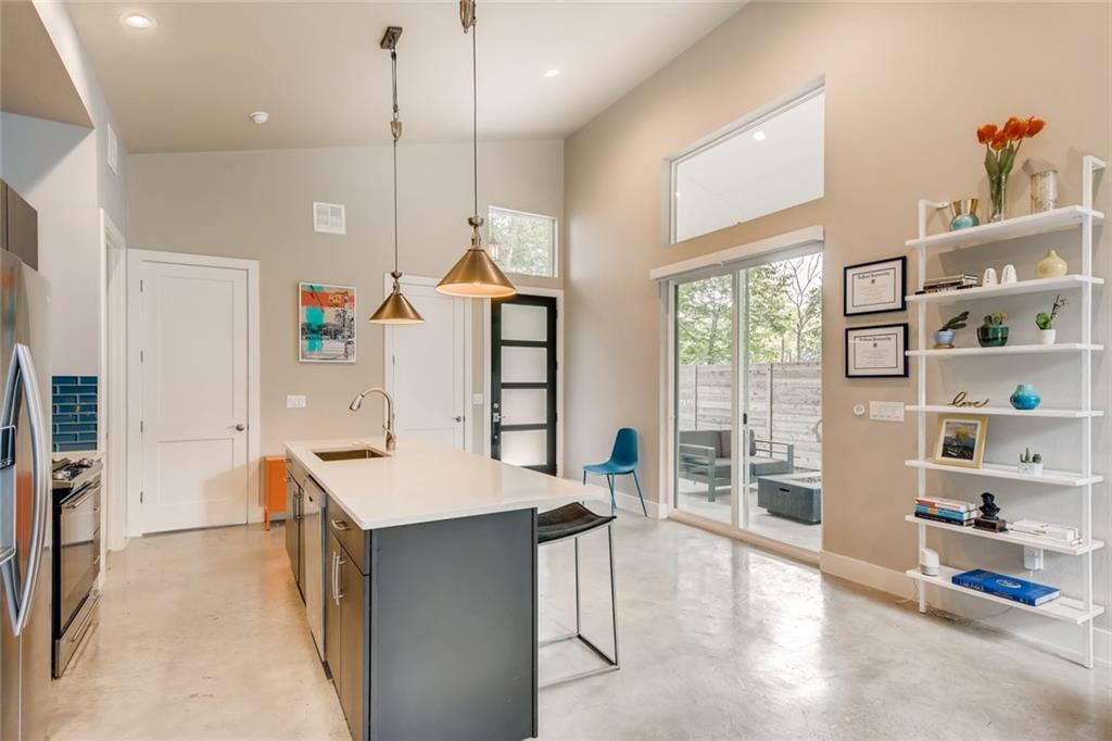 1142 Eleanor Street, Unit 2 Austin, TX 78721 - Photo 7 of 24 A contemporary kitchen features an island, stainless steel appliances, and sleek concrete flooring.
