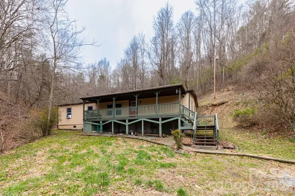 a view of a house with a yard and large trees