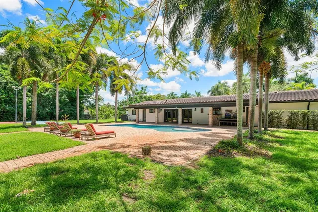 a living room with stainless steel appliances furniture a rug and a kitchen view