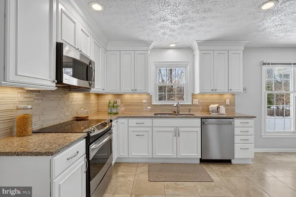 a kitchen with stainless steel appliances granite countertop a stove sink and microwave
