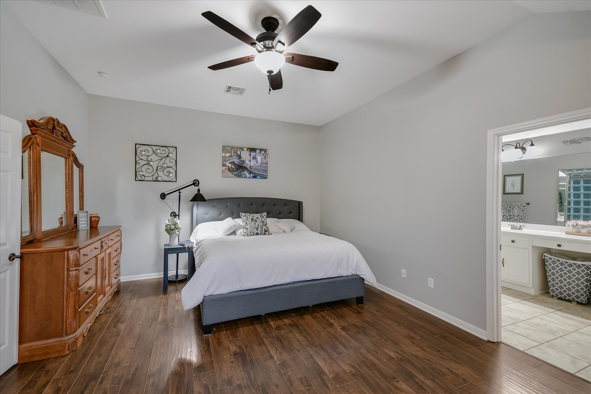 300 Wesley Ridge Drive Spicewood, TX 78669 - Photo 19 of 40 Main-level primary suite offers privacy and comfort with a vaulted ceiling, spacious layout, and a beautiful arched window overlooking the backyard—set apart from the other three lower-level bedrooms for a peaceful retreat.