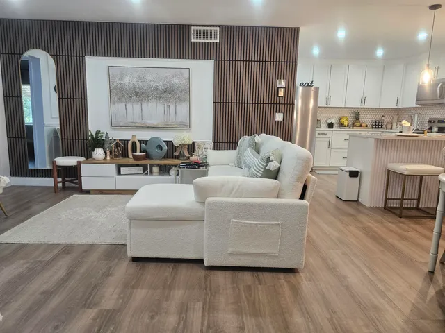 a living room with furniture kitchen view and a chandelier