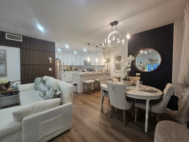 a living room with couches a dining table and kitchen view with wooden floor