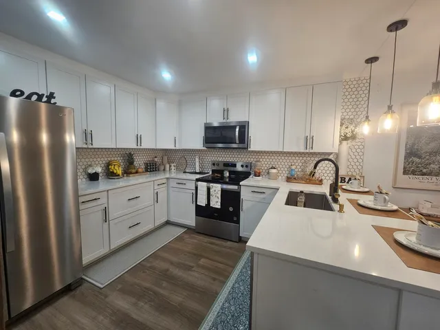 a kitchen with stainless steel appliances granite countertop a sink a stove a refrigerator and island with wooden floor