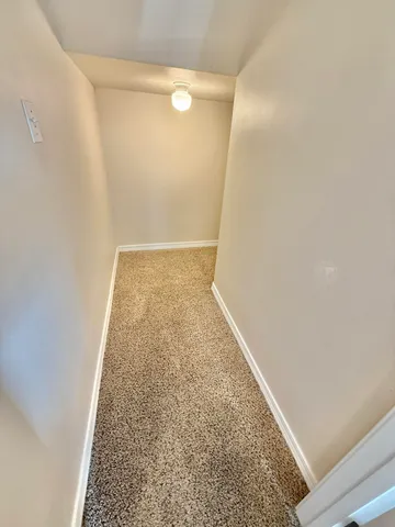 an empty room with a chandelier fan and windows