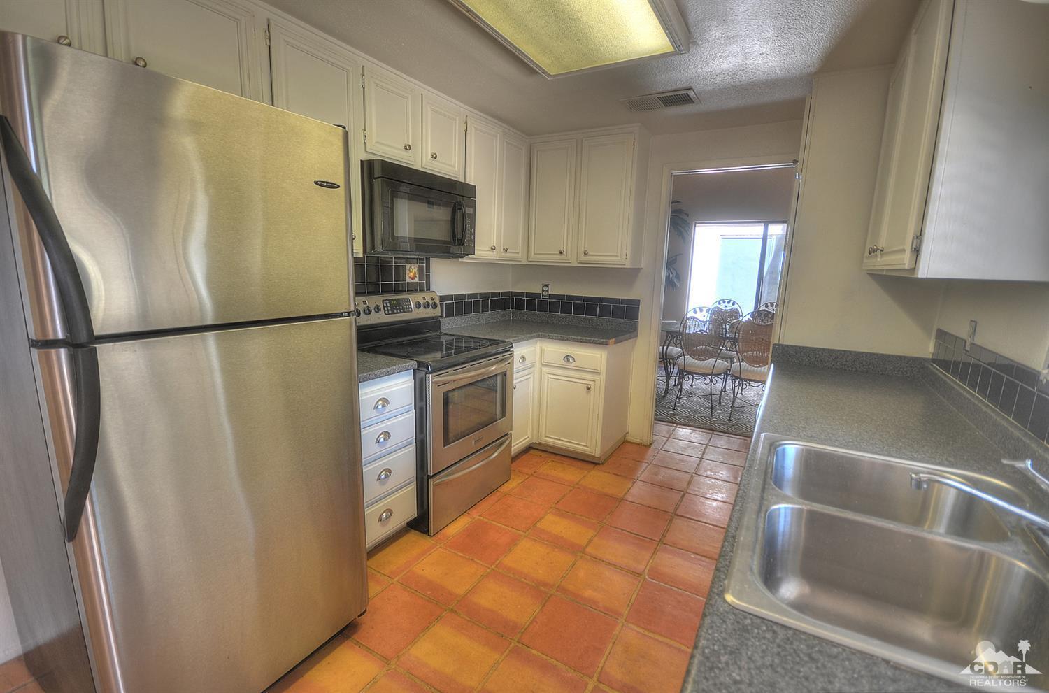 72386 Ridgecrest Lane Palm Desert, CA 92260 - Photo 8 of 38 a kitchen with stainless steel appliances a refrigerator a stove a sink a washer dryer and white cabinets