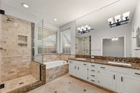 a bathroom with a granite countertop double vanity sink a large mirror and shower
