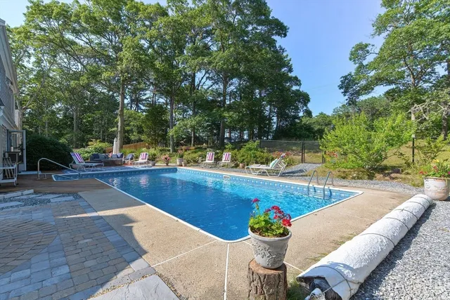 a view of swimming pool with seating space and trees in the background