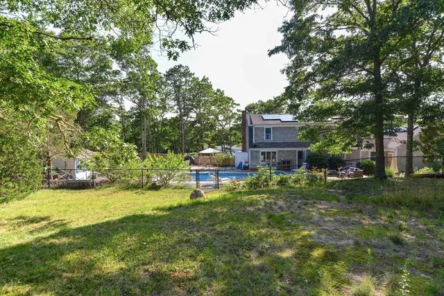 a view of a house with a big yard and large trees
