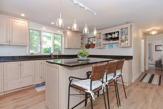 a kitchen with stainless steel appliances granite countertop a sink a stove a dining table and chairs