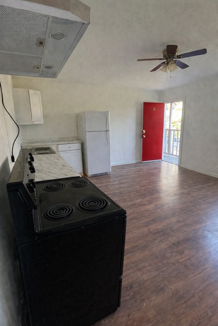 211 West Washington Street, Unit 4 Seguin, TX 78155 - Photo 2 of 7 Kitchen with ventilation hood, range with electric stovetop, freestanding refrigerator, laminate flooring