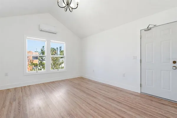 a view of an empty room with window and wooden floor
