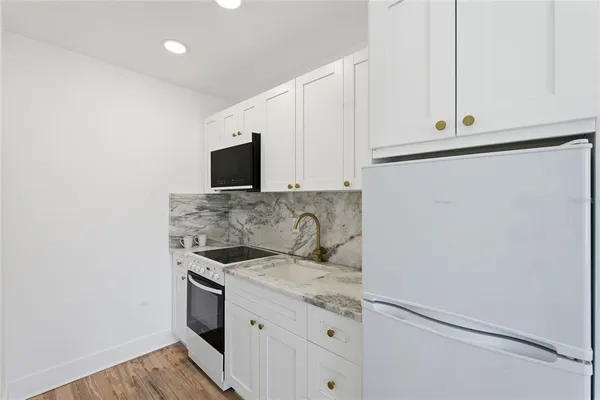 a kitchen with granite countertop white cabinets and stainless steel appliances