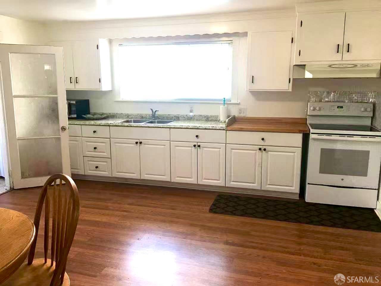 550 A Street Hayward, CA 94541 - Photo 6 of 14 a kitchen with stainless steel appliances granite countertop a stove a sink and white cabinets with wooden floors
