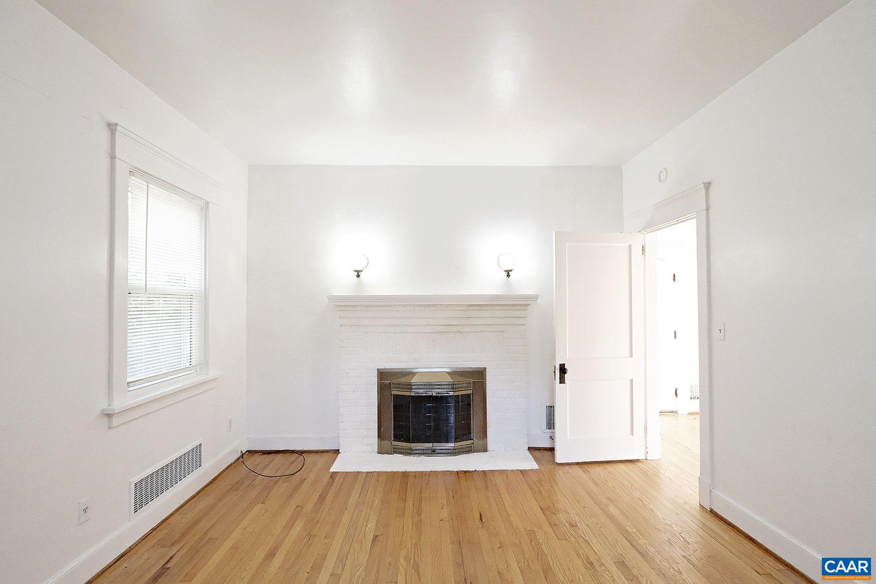 an empty room with wooden floor and fireplace