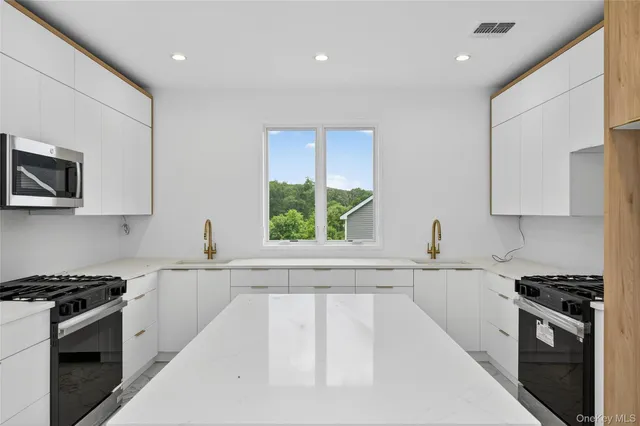 a kitchen with stainless steel appliances a sink stove and white cabinets