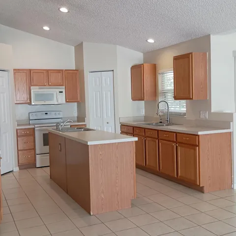 a kitchen with kitchen island granite countertop a sink counter top space and cabinets