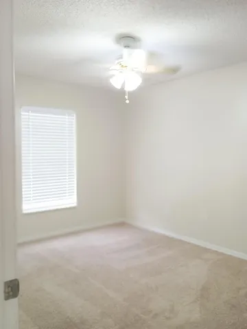 an empty room with a window and a chandelier fan