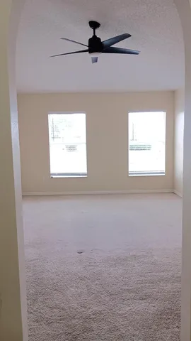 an empty room with a window and a ceiling fan