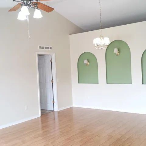 a view of a livingroom with chandelier fan and wooden floor