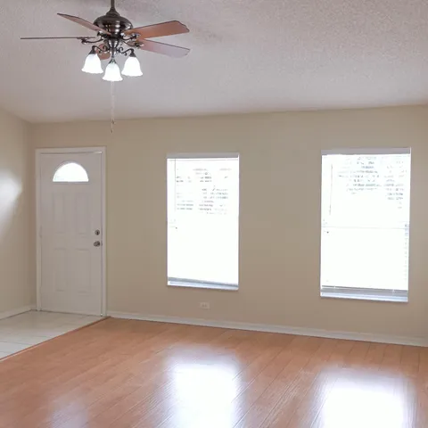 a view of an empty room with a window and wooden floor
