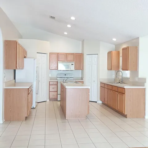 a large kitchen with a refrigerator a sink dishwasher with a stove and cabinets