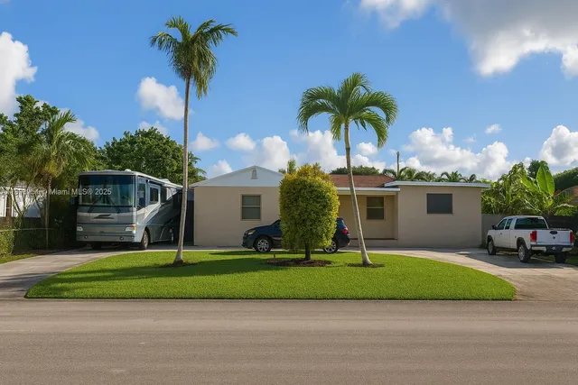 a front view of a house with a yard and palm trees