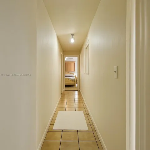 a view of a hallway with wooden floor and a bathroom