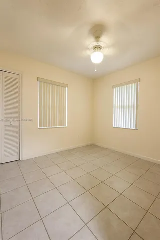 an empty room with windows and ceiling fan