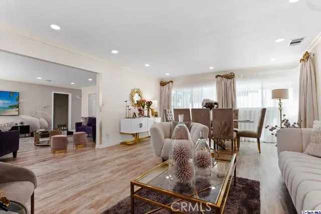a living room with furniture kitchen view and a wooden floor