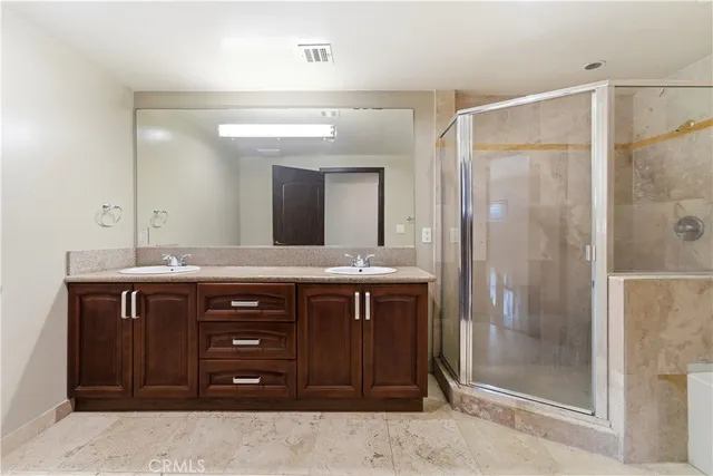 a bathroom with a granite countertop sink a mirror and a shower