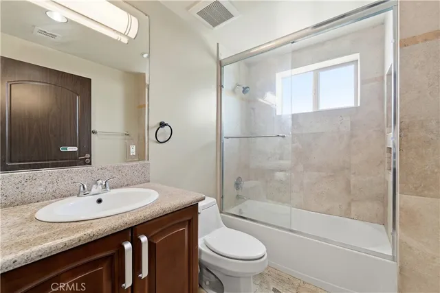 a bathroom with a granite countertop sink toilet and shower
