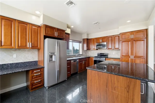 a kitchen with stainless steel appliances granite countertop a refrigerator stove and sink