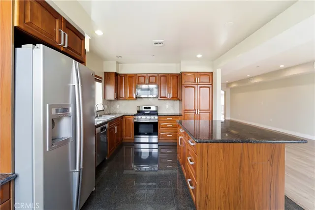 a kitchen with stainless steel appliances granite countertop a refrigerator a stove a sink and a microwave