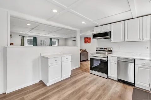 a kitchen with cabinets stainless steel appliances and wooden floor