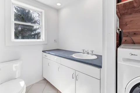 a bathroom with a granite countertop sink and a toilet