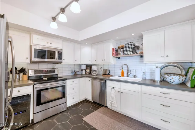 a kitchen with granite countertop white cabinets and stainless steel appliances