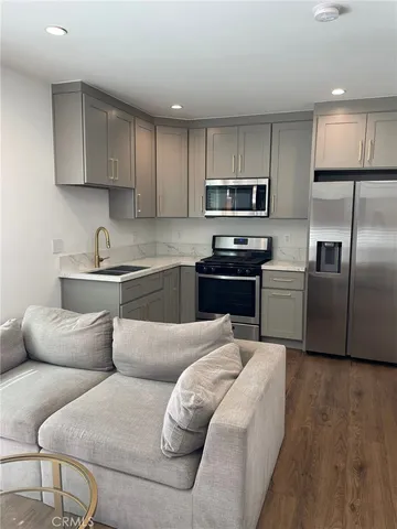 a kitchen with stainless steel appliances granite countertop a refrigerator a sink a stove top oven a counter space and cabinets