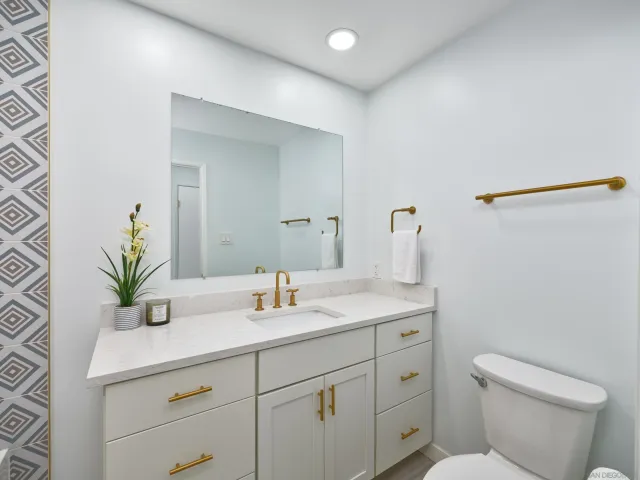 a bathroom with a granite countertop sink a toilet and mirror