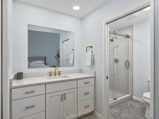 a bathroom with a shower sink vanity mirror and toilet