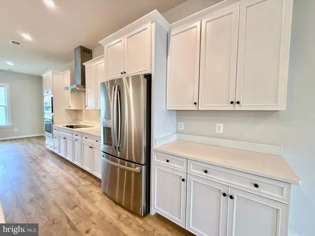 a large kitchen with kitchen island a large island a sink a stove and wooden floors