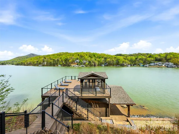 a view of a chairs and table on wooden deck with lake view