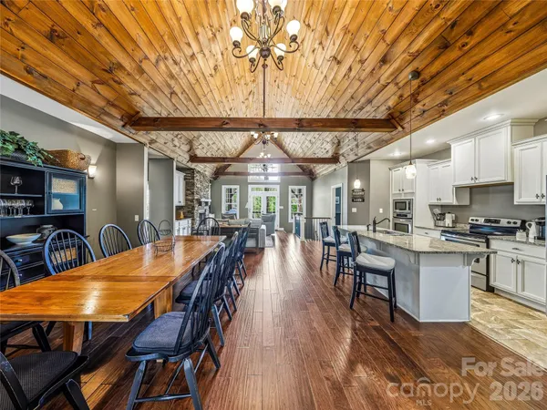 a kitchen with stainless steel appliances kitchen island granite countertop a dining table chairs and a refrigerator