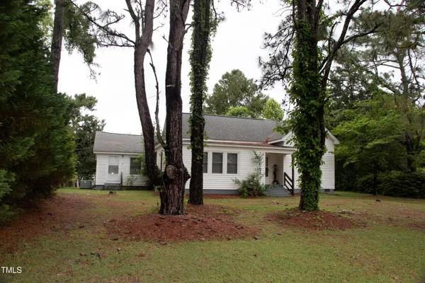a view of a small white house and a yard