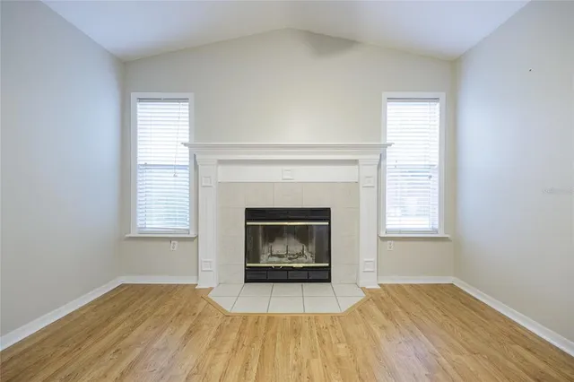 an empty room with wooden floor fireplace and window