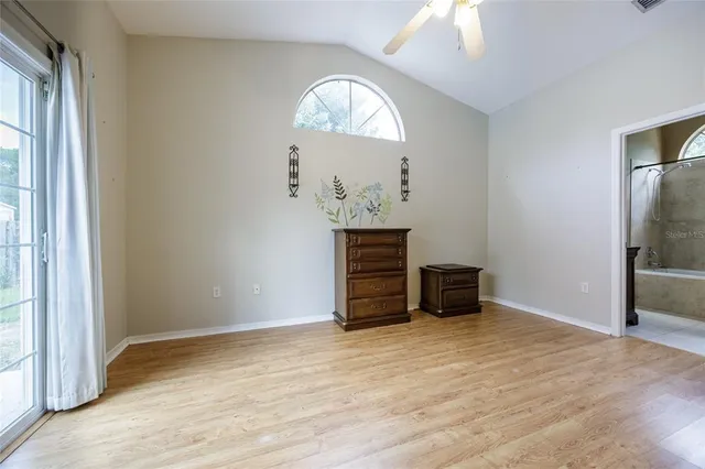 an empty room with a window and a chandelier fan