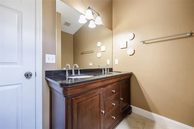 a bathroom with a granite countertop sink a light fixture and a mirror