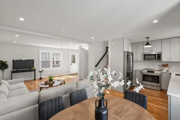 a living room with furniture potted plant and kitchen view